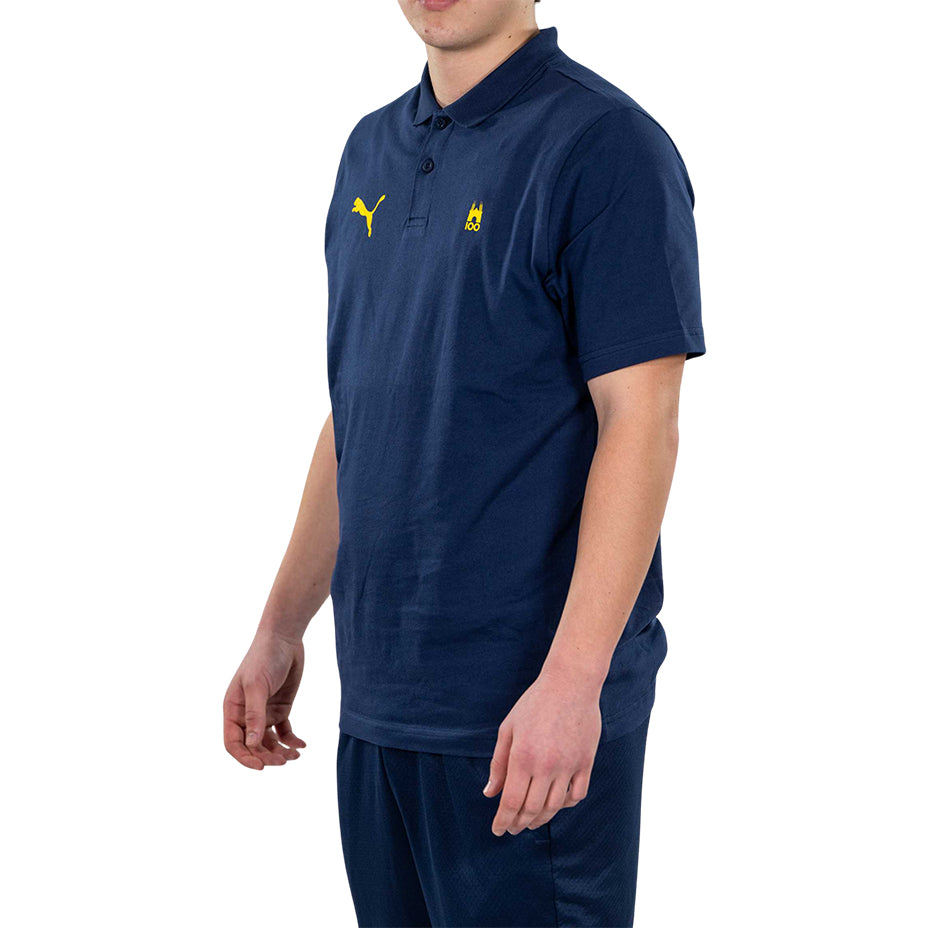 Ragazzo indossa polo blu con logo tardini 100 e puma giallo