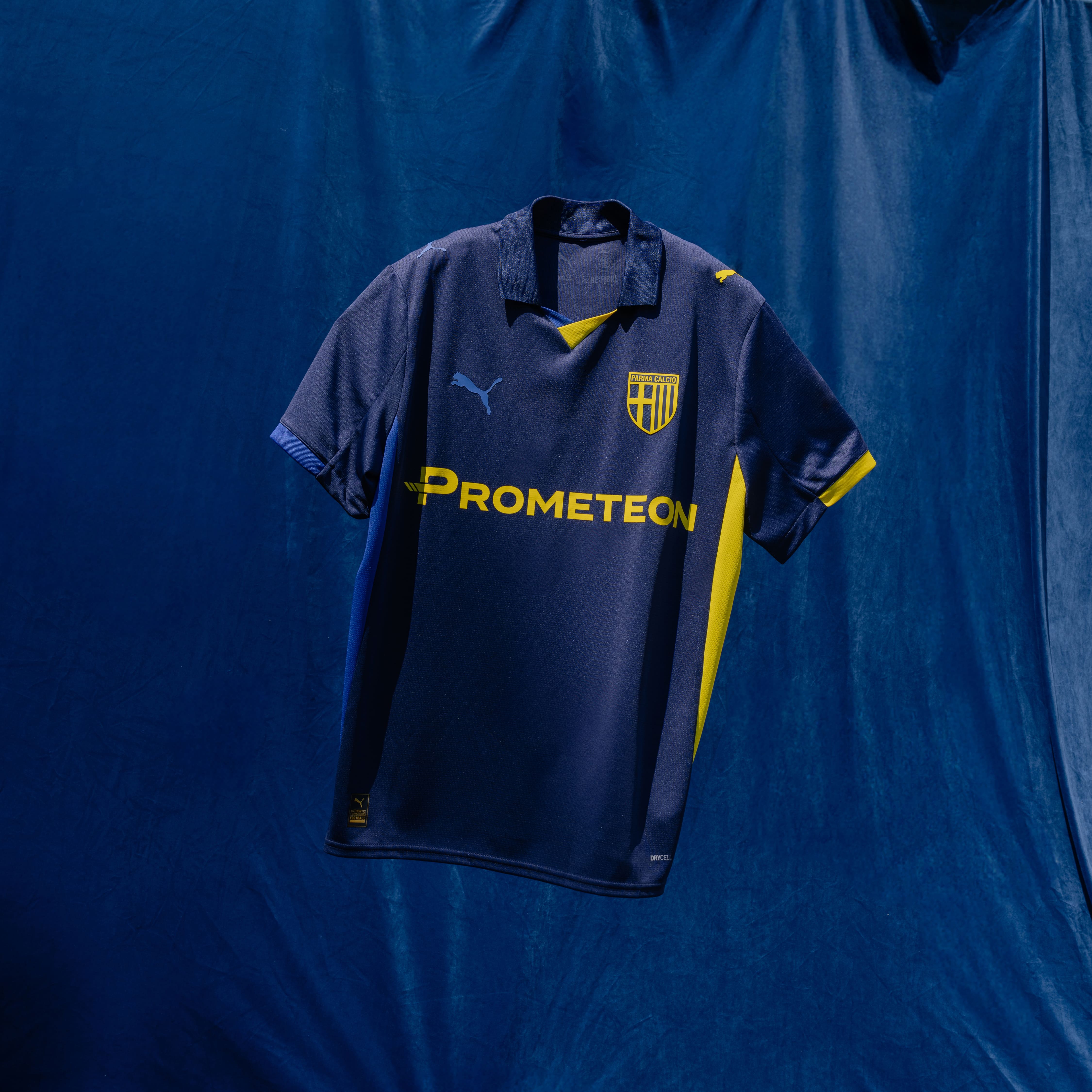 Foto maglia gara Fourth con sponsor giallo prima squadra Maschile Prometeon. Maglia blu navy con colletto, dettagli laterali e dettagli maniche blu e gialli.