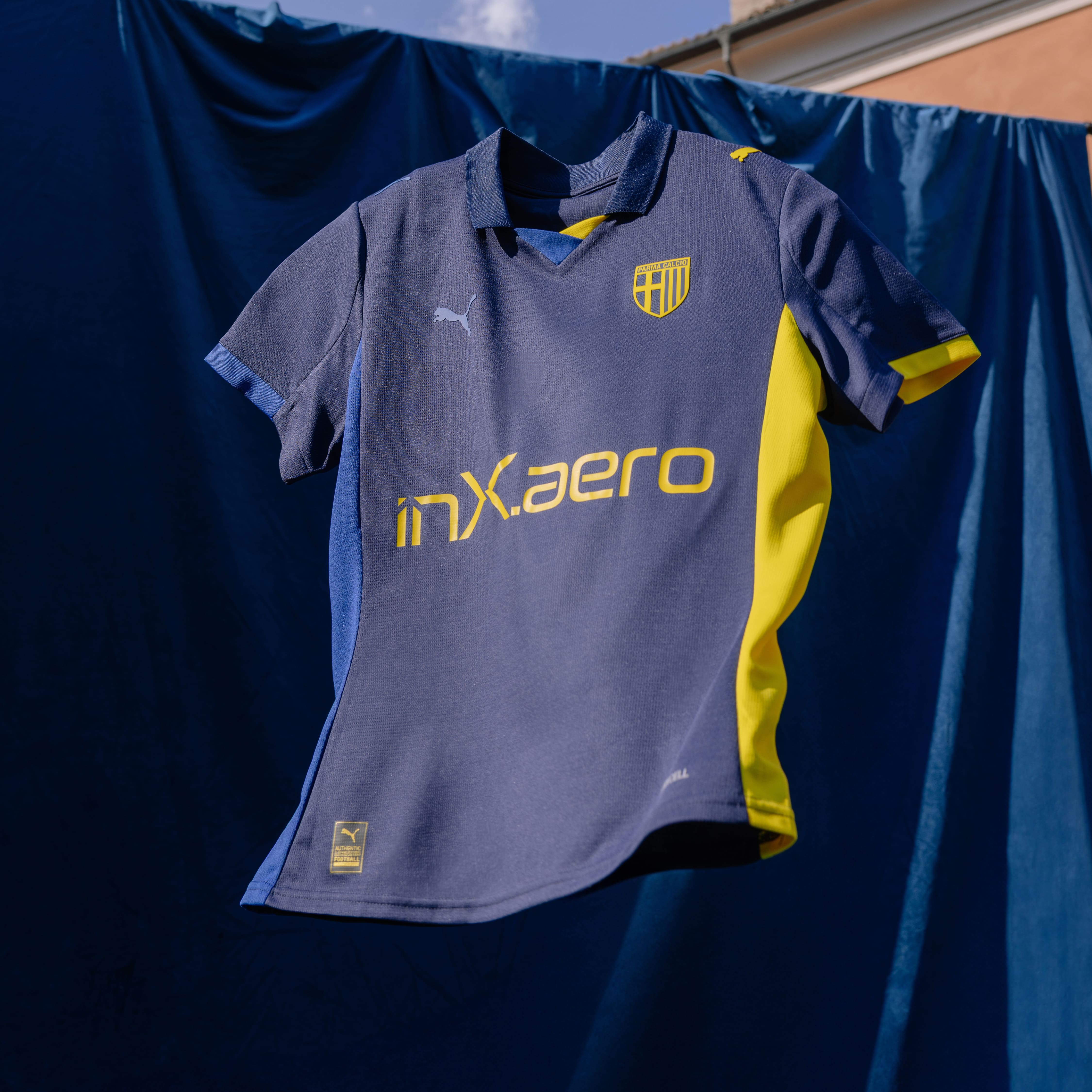 Foto maglia gara Fourth con sponsor gialli prima squadra Femminile. Maglia blu navy con colletto, dettagli laterali e dettagli maniche blu e gialli.